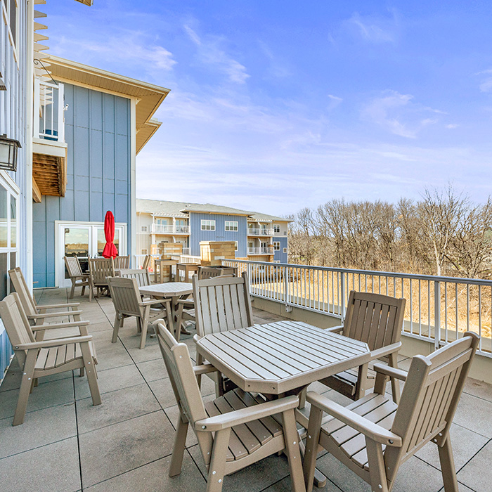 Outdoor deck with tables and umbrellas for independent living and assisted living at Harbor Crossing.