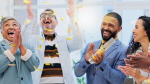 Four coworkers celebrate together in a shower of confetti.