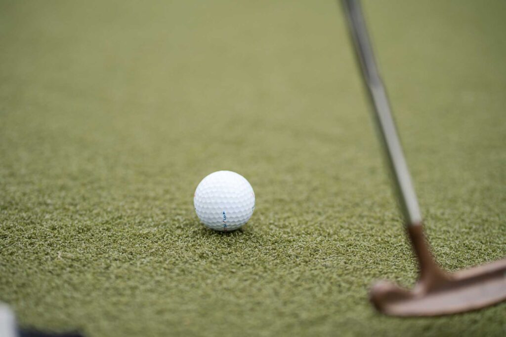 Closeup of golf ball and putter.