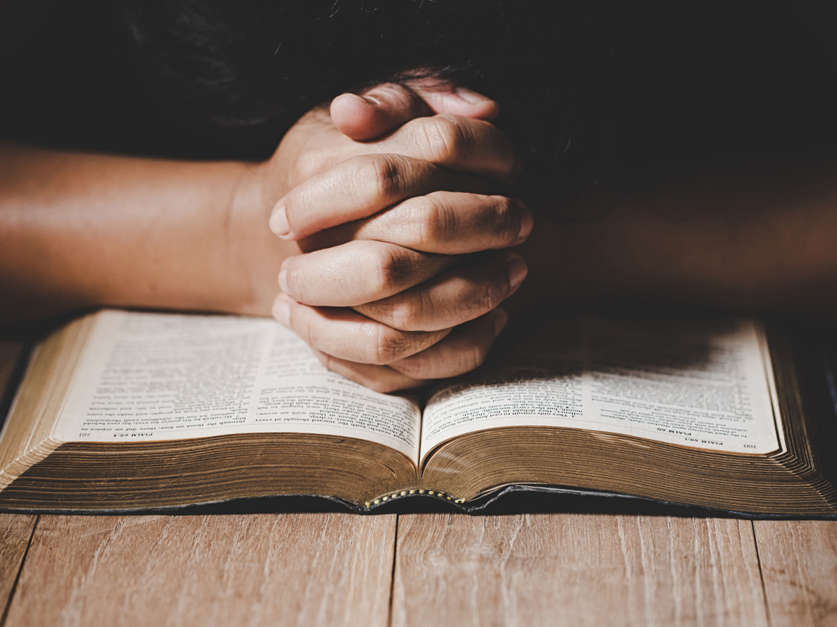 Hands folded on Bible.