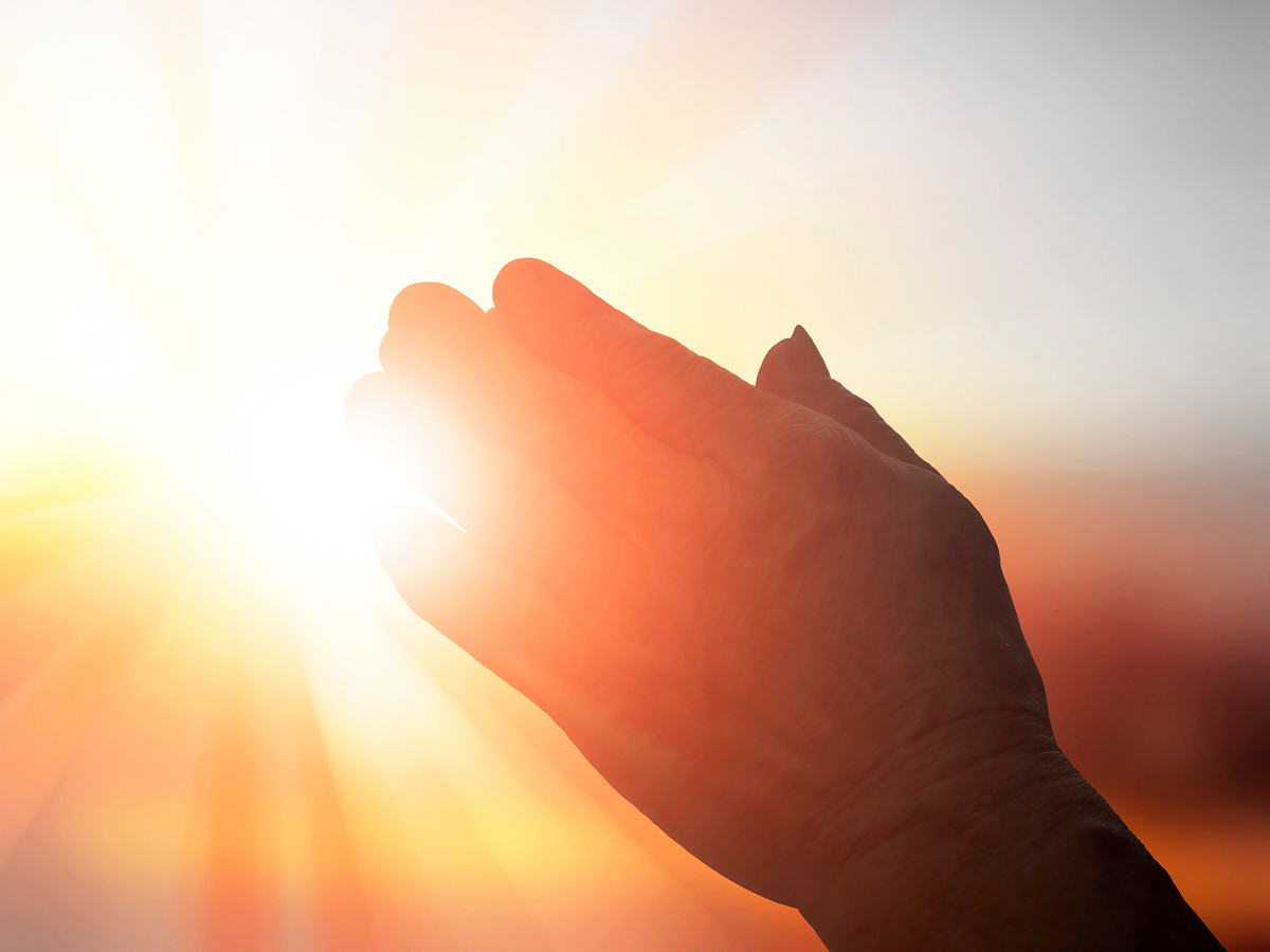 image of praying hands and sunlight